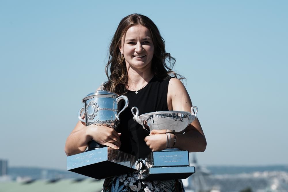 Czech Republic's Barbora Krejcikova holds the French Open tennis tournament women's cup, left, and women's doubles cup during a photocall Monday, June 14, 2021 in Paris. French Open champion Barbora Krejcikova completed a rare sweep of titles at Roland Garros as she won a third women's doubles major trophy with fellow Czech teammate Katerina Siniakova on Sunday. (AP Photo/Thibault Camus)